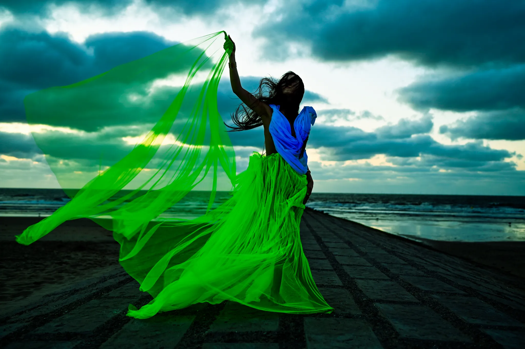 Green fabric flowing in the wind under a stormy sky